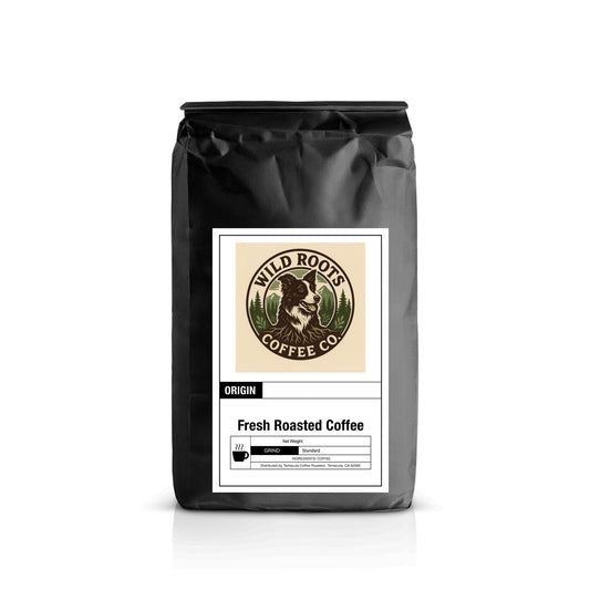 Black coffee bag with Wild Roots Coffee Co. logo featuring a raccoon and green trees, labeled Fresh Roasted Coffee.